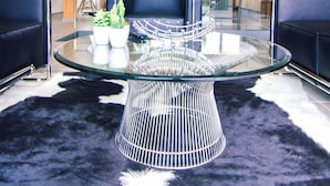 Una sala de estar moderna con una mesa de centro de vidrio, sofás de cuero negro y una escalera que conduce a un nivel superior.