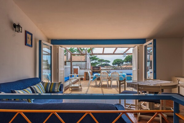A cozy patio area with a blue sofa, a dining table, and chairs.
