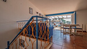 A spacious living area with a staircase, a sofa, and a dining table.