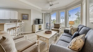 A spacious living room with a sofa, chairs, a TV, and a dining area.