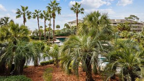 A resort with palm trees, a swimming pool, and a building with balconies.