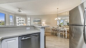 A modern kitchen with a stainless steel refrigerator, a dishwasher, and a dining area with a table and chairs.
