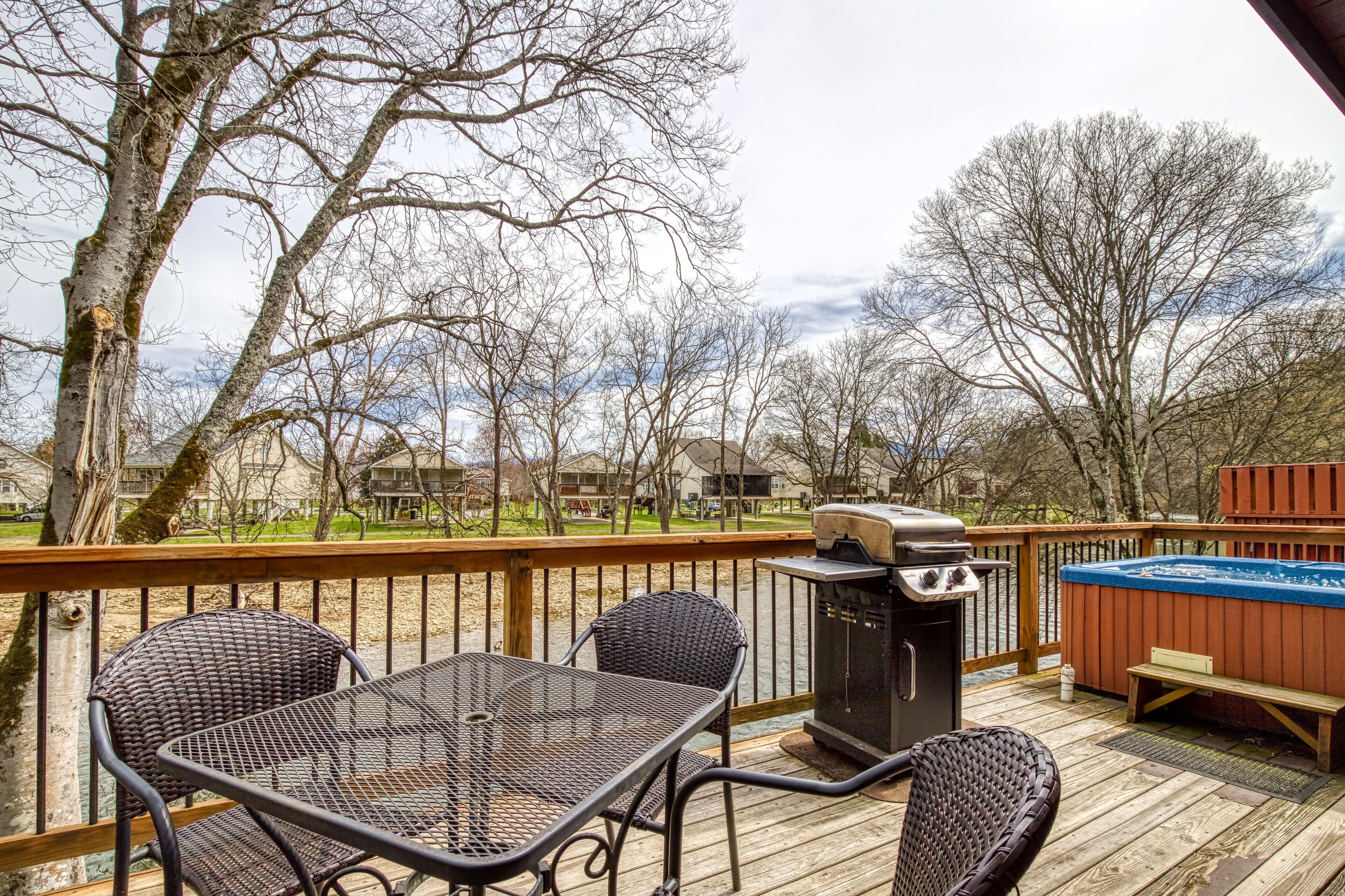 A wooden deck with a grill, hot tub, and wicker furniture.
