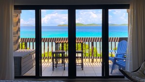 A balcony with a view of the ocean, a chair, and a table.