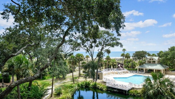 Ein Resort mit Swimmingpool, Liegestühlen und Meerblick.