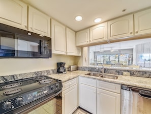 A kitchen with white cabinets, a black stove, a microwave, a coffee maker, and a dishwasher. - Beautiful 2nd Floor Villa with Ocean Views in Palmetto Dunes (Hilton Head Island)