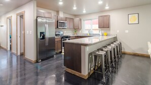 Une cuisine moderne dotée d’appareils électroménagers en acier inoxydable, de meubles en bois et d’un îlot central avec des tabourets de bar.