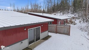 Un bâtiment rouge avec un toit en métal et une clôture en bois.