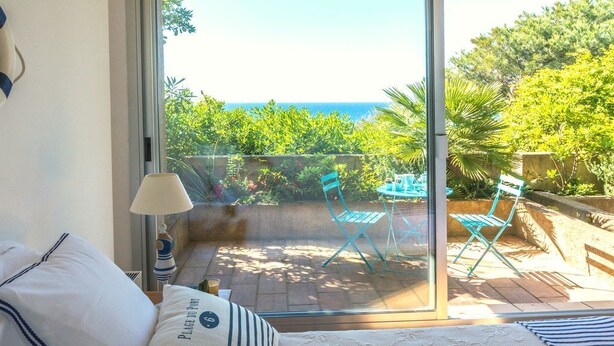 Une chambre avec vue sur un patio et la mer.