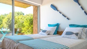 Une chambre avec deux lits, une grande fenêtre et deux pagaies accrochées au mur.