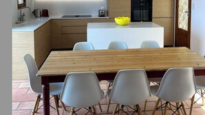 Une cuisine moderne dotée d’un îlot central, d’une table à manger avec des chaises et d’un luminaire suspendu.