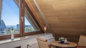Um canto acolhedor com vista para a cidade, uma mesa com cadeiras e um objeto decorativo no parapeito da janela.