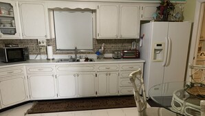 A kitchen with white cabinets, a sink, a microwave, a toaster, and a refrigerator. - Clean And Comfortable  (Sebring)