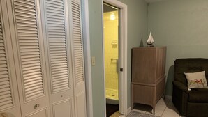 A room with a closed door, a wooden cabinet, a dark-colored sofa with a cushion, and a patterned rug. - Clean And Comfortable  (Sebring)