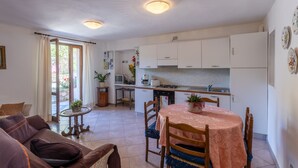 A compact kitchen with white cabinets, a dining table with chairs, and a small side table with a plant. - CASA RITA - AP. N. 4 LAKE GARDA TREMOSINE (Vesio)