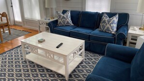 A living room with a blue sofa, white coffee table, and patterned rug. - Private condo in Maushop. Steps to beach, ocean, Popponesset Inn and Marketplace (Mashpee)