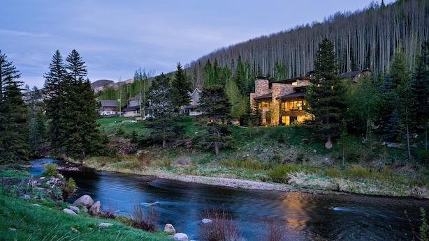 Une propriété située au bord de la rivière, avec une maison en pierre, entourée d’une forêt dense et traversée par un petit ruisseau.