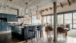 Une cuisine moderne dotée d’un îlot central, de tabourets de bar et d’un pare-feu en pierre.