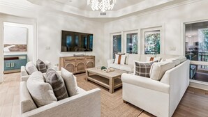 A spacious living room with a large flat-screen TV, a wooden cabinet, and a sofa set. - Picturesque Villa w/ Screened Porch & Amenities (Hilton Head Island)