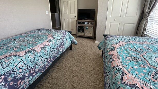 A hotel room with two beds, a television, and a small cabinet. - 4 bedroom townhouse at The Villas at seven Dwarfs (Kissimmee)