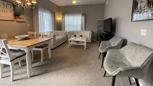 A living room with a dining table, two sofas, a coffee table, a TV, and a ceiling fan. - 4 bedroom townhouse at The Villas at seven Dwarfs (Kissimmee)