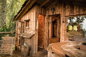 A wooden cabin with a wooden deck, a bench, and a small table.