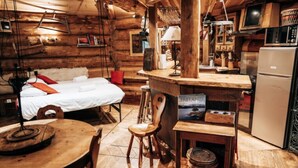 L’intérieur d’un chalet confortable, avec une chambre, une table à manger en bois et un coin cuisine.