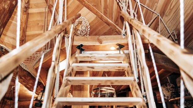 Un intérieur en bois, avec un escalier en bois et un lustre.