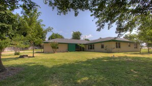 A single-story house with a green door, a covered porch, and a small yard. - Close to a Vibrant and fun DownTown Rose District. 15 min from Tulsa. (Broken Arrow)