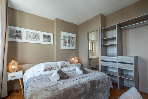A bedroom with a large bed, bedside tables, a wardrobe, and wall art.