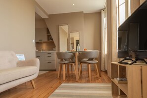A modern living room with a sofa, dining table, chairs, and a TV.