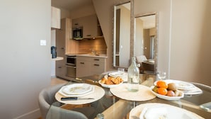 A modern dining area with a glass table, plates, and a bottle of water. - Les Mouailleries on the ground floor 2 bedrooms 2 bathrooms (Honfleur)