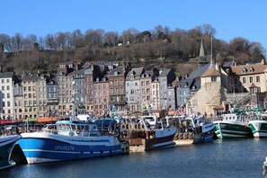 A harbor with boats docked, a church steeple, and a row of buildings along the water's edge.