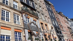 A row of multi-story buildings with balconies, large windows, and a heart-shaped decoration on one window. - Les Mouailleries on the ground floor 2 bedrooms 2 bathrooms (Honfleur)