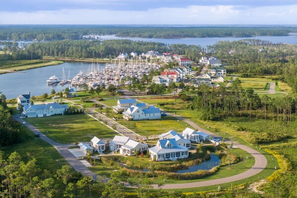 An aerial view of a coastal residential area with houses, a marina, and a lake. - Sweetwater - Pet Friendly in River Dunes Community (Oriental)