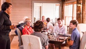A group of people seated at a table in a room with wooden walls and a large window. - Sweetwater - Pet Friendly in River Dunes Community (Oriental)