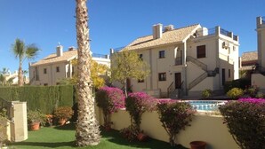 A residential building with a swimming pool, a well-maintained lawn, and potted plants. - App,  2 bedroom ,2 terraces, Swimming pool + Parking, Wifi (Algorfa)