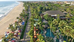 A resort with a beach view, a swimming pool, and a row of palm trees. - Interconnection Hostel (Kuta)