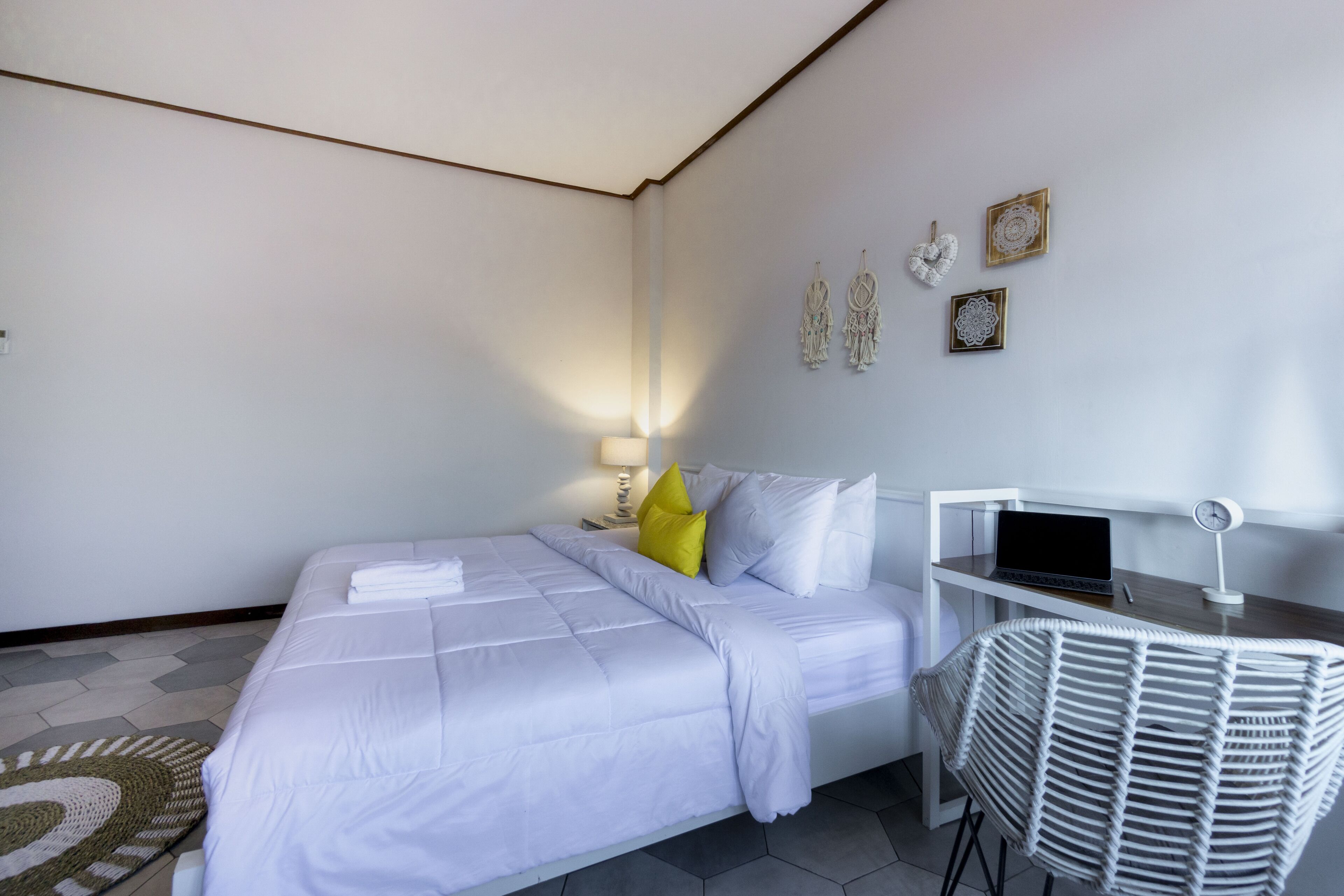 A hotel room with a bed, a desk with a laptop, a chair, and wall decorations.