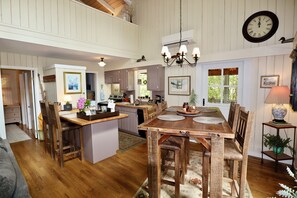 Un'ampia cucina con mobili in legno, una zona pranzo con un grande tavolo in legno e un lampadario a sospensione.