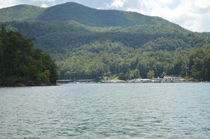 A lakeside property with a dock, boats, and a mountain backdrop. - Overlook Watauga Lake, log cabin- BOAT DOCK, HOT TUB & FIRE PIT (Butler)