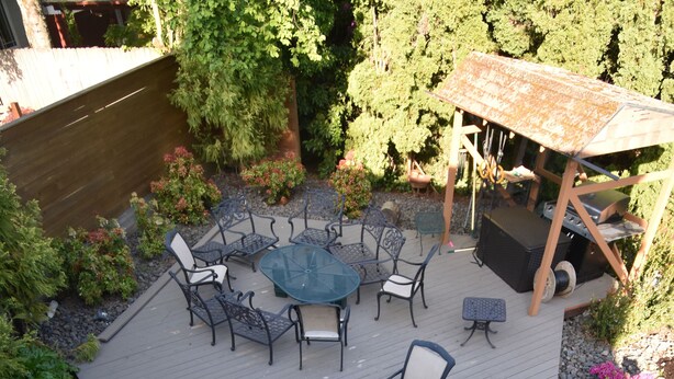 A patio with a round table and chairs, surrounded by a stone pathway and greenery. - Two Stories Cottage in SE Portland Oregon (Portland)