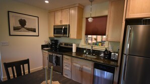 A modern kitchen with stainless steel appliances, wooden cabinets, and a dining table with candles. - Two Stories Cottage in SE Portland Oregon (Portland)