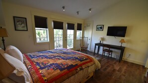 A bedroom with a large bed, a desk, a chair, and a television. - Two Stories Cottage in SE Portland Oregon (Portland)