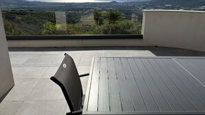 Un balcon offrant une vue sur un paysage montagneux et un plan d’eau.