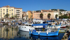Un port de plaisance où sont amarrés des bateaux, entouré de bâtiments aux couleurs vives et sous un ciel dégagé.