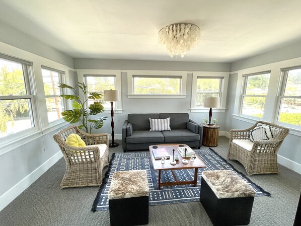 A living room with a gray sofa, two wicker chairs, a coffee table, and a patterned rug.