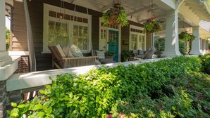 A porch with a bench, hanging planters, and a door with a blue frame. - Classic VAHi Bungalow (Atlanta)