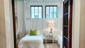 A bedroom with a bed, bedside table, lamp, and a view of the outside through a window. - Classic VAHi Bungalow (Atlanta)