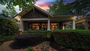 A two-story house with a covered porch, a brick pathway, and a garden with various plants and flowers. - Classic VAHi Bungalow (Atlanta)